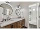 Bright bathroom featuring a dual sink vanity, round mirrors and a tiled shower visible through doorway at 2625 N 24Th St # 15, Mesa, AZ 85213