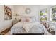 Charming bedroom with floral bedding, decorative mirror, and a bright window showcasing the pleasant exterior at 2625 N 24Th St # 15, Mesa, AZ 85213