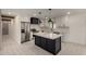 Modern kitchen boasts white cabinets, a black island with marble countertop, and stainless steel appliances at 313 N 101St Way, Mesa, AZ 85207