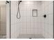 This tiled shower features a black shower head and trim, a built in niche, and black and white flooring at 313 N 101St Way, Mesa, AZ 85207