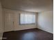 Spacious living room featuring new dark wood floors, a large window, and a front door at 3810 N Maryvale Pkwy # 2077, Phoenix, AZ 85031