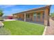 Well-maintained backyard has a covered patio, artificial grass, and desert landscaping at 40479 W Marion May Ln, Maricopa, AZ 85138