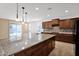 Bright kitchen featuring wood cabinets, granite countertops, and a center island with a backyard view at 40479 W Marion May Ln, Maricopa, AZ 85138