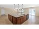 Large kitchen island with sink and dishwasher, complemented by wood cabinets and tile floors at 40479 W Marion May Ln, Maricopa, AZ 85138