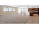 Bright, open-concept living room with large windows and neutral tones flowing into the kitchen area at 40479 W Marion May Ln, Maricopa, AZ 85138