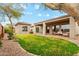 Well-manicured backyard with lush green grass, covered patio seating area, a guest house, and desert landscaping at 40614 N Harbour Town Ct, Anthem, AZ 85086