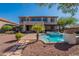 Expansive backyard featuring a swimming pool, spa, covered patio, mature landscaping, and two-story home at 4264 S Columbine Way, Gold Canyon, AZ 85118