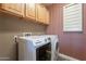 Modern laundry room featuring a front load washer and dryer and wood cabinetry at 4264 S Columbine Way, Gold Canyon, AZ 85118
