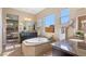 Bright bathroom with dual vanities, soaking tub under large window, neutral tile, and view of bedroom at 6917 E Ingram Cir, Mesa, AZ 85207
