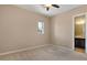 Inviting bedroom with light carpet, window, ceiling fan, and ensuite bathroom access, offering a comfortable and functional space at 6917 E Ingram Cir, Mesa, AZ 85207