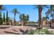 View of the gated entrance into the Annecy community with manicured flowers and lush palm trees at 6917 E Ingram Cir, Mesa, AZ 85207