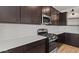 Well-appointed kitchen featuring stainless steel appliances, white backsplash, and dark wood cabinetry at 7327 S 76Th Ln, Laveen, AZ 85339