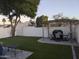 Backyard featuring lush artificial turf, a patio dining area with a grill, and mature trees, perfect for outdoor entertaining at 8879 E Friess Dr, Scottsdale, AZ 85260