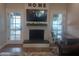 Cozy living room with a charming fireplace, hardwood floors, and double french doors leading to the backyard at 8879 E Friess Dr, Scottsdale, AZ 85260