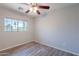 A neutral bedroom featuring sleek, modern wood-look flooring, a ceiling fan, and a window for natural light at 931 S Racine Ln, Gilbert, AZ 85296