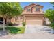 Two-story tan home showcasing a two-car garage, complimented by a lush lawn and mature trees at 931 S Racine Ln, Gilbert, AZ 85296