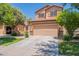 Two-story tan home featuring a two-car garage, well-maintained lawn and mature landscaping at 931 S Racine Ln, Gilbert, AZ 85296