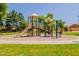 A playground is surrounded by green grass and mature trees at 931 S Racine Ln, Gilbert, AZ 85296