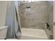 Bathroom with a bathtub, gray tile walls, and a shower head at 9759 E Brown Rd, Mesa, AZ 85207