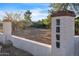 Entrance gate featuring a stucco column with decorative tile address numbers, set against a backdrop of desert foliage at 1044 E Irvine Rd, Phoenix, AZ 85086