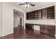 A home office area features a built-in desk, shelving, and a ceiling fan, with dark wood-look floors at 10910 E Sebring Ave, Mesa, AZ 85212