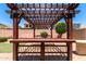 Wooden pergola offers shade and style to the backyard with BBQ area and fire pit at 10910 E Sebring Ave, Mesa, AZ 85212