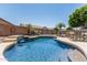 Beautiful backyard pool with a waterfall feature, surrounded by desert landscaping and a safety fence at 12325 W Berridge Ln, Litchfield Park, AZ 85340