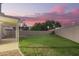 Backyard featuring green grass, covered patio, block fence, and clear view of the beautiful sunset sky at 1405 N Jamaica Way, Gilbert, AZ 85234