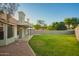 Backyard featuring green grass, home's covered patio, and brick perimeter near fence and house at 1405 N Jamaica Way, Gilbert, AZ 85234