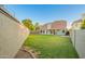 Backyard with lush green grass, home's covered patio, and a block fence at 1405 N Jamaica Way, Gilbert, AZ 85234