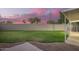 Backyard featuring green grass, covered patio, and block fence with clear view of the beautiful sunset sky at 1405 N Jamaica Way, Gilbert, AZ 85234