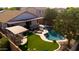 Gorgeous backyard featuring a private pool, artificial grass, covered patio, and outdoor kitchen area, perfect for relaxation at 1432 E Penny Ln, San Tan Valley, AZ 85140