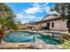 Private backyard featuring a sparkling pool with rock accents, lounge chairs, outdoor kitchen, and covered patio at 1432 E Penny Ln, San Tan Valley, AZ 85140
