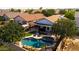 Aerial view of a backyard oasis featuring a freeform pool, patio with pergola, lush landscaping, and verdant artificial turf at 1432 E Penny Ln, San Tan Valley, AZ 85140