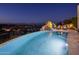 Sparkling pool with a rock waterfall, surrounded by lush landscaping and city views at twilight at 15054 E Sundown Dr, Fountain Hills, AZ 85268