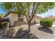 Tan home featuring stone accents, a well-manicured yard, and mature trees providing ample shade at 15429 W Ventura St, Surprise, AZ 85379