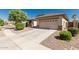 A beige house has a garage, a driveway, and green bushes out front, nestled in a sunny neighborhood at 15429 W Ventura St, Surprise, AZ 85379