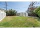 Large grassy backyard with a detached garage and privacy bushes at 1609 W Lewis Ave, Phoenix, AZ 85007