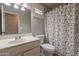 Bathroom features a vanity with a mirror, toilet, and a shower with a floral curtain at 1814 N 89Th Ave, Phoenix, AZ 85037