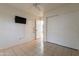 Bright bedroom featuring tile flooring, a sliding door closet, and a wall-mounted television at 1814 N 89Th Ave, Phoenix, AZ 85037