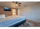 Bedroom view showing TV, a glimpse into the en suite bathroom, and ceiling fan at 1814 N 89Th Ave, Phoenix, AZ 85037