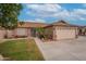 Inviting single-story home features a well-manicured lawn, mature trees, and an expansive driveway with a two-car garage at 1814 N 89Th Ave, Phoenix, AZ 85037