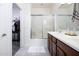 Bright bathroom featuring a double sink vanity and glass-enclosed shower, adjacent to the walk-in closet at 18809 E Seagull Dr, Queen Creek, AZ 85142
