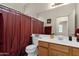 Bright bathroom featuring a single vanity, framed mirror, and a bathtub with a red shower curtain at 1960 S Falcon Dr, Gilbert, AZ 85295