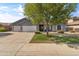 Charming single-story home with a well-manicured lawn, mature tree, three-car garage, and stone accents at 20464 E Bronco Dr, Queen Creek, AZ 85142