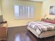 Cozy bedroom featuring a hardwood floor, plantation shutters, and a comfortable queen-size bed at 2122 N Stapley Dr, Mesa, AZ 85203