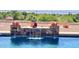Backyard with a beautiful pool with a rock waterfall feature, lush greenery, and privacy fence at 2122 N Stapley Dr, Mesa, AZ 85203
