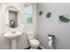 Well-lit half bath with a pedestal sink, decorative wall plants, and a stylish round mirror at 24013 N 165Th Ave, Surprise, AZ 85387