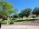 Enjoy the community park with lush green spaces, mature trees, and a colorful playground under a clear blue sky at 24013 N 165Th Ave, Surprise, AZ 85387