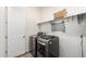 Functional laundry room with modern washer and dryer, shelving, and a storage basket at 24013 N 165Th Ave, Surprise, AZ 85387